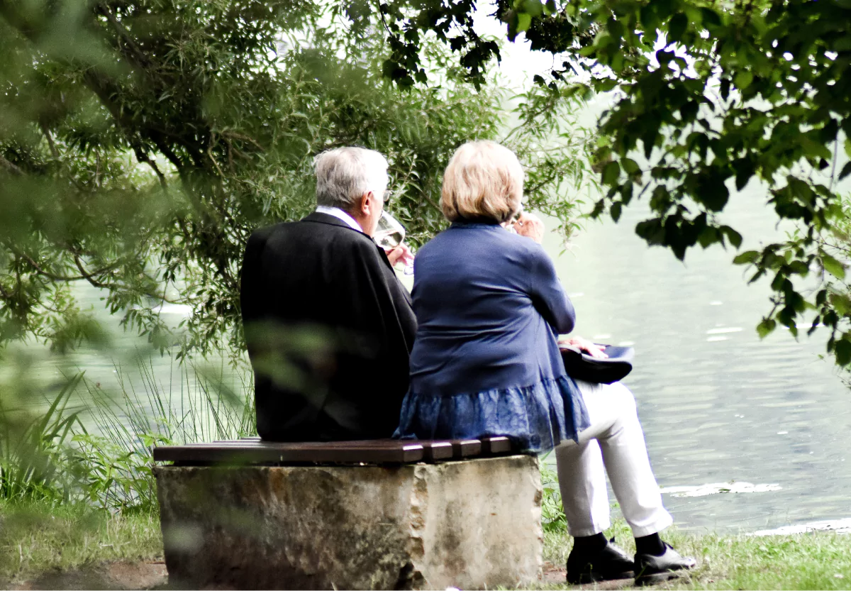 two elderly people drinking wine outside